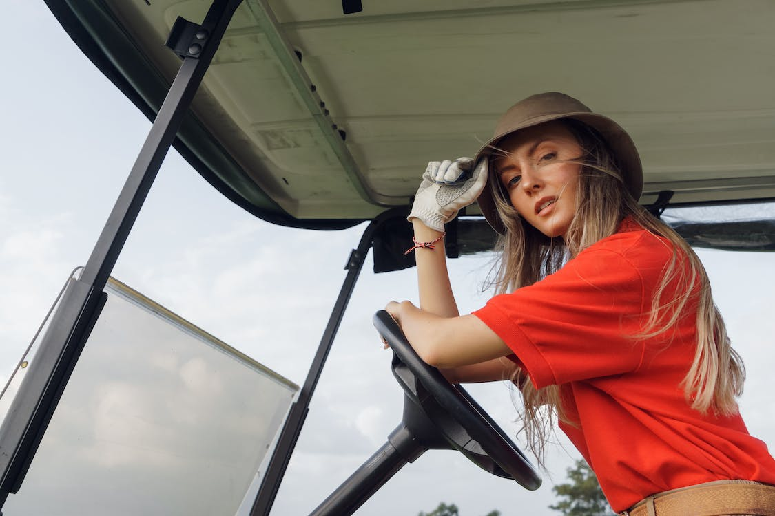 Woman in red polo shirt driving a golf cart
