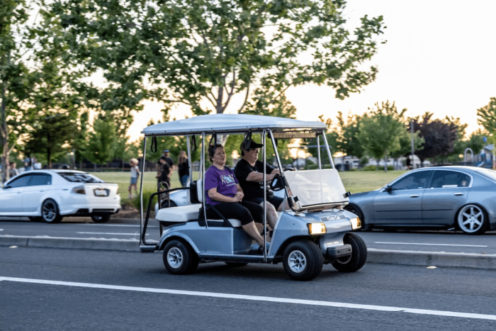 Couple riding a golf cart with lights on