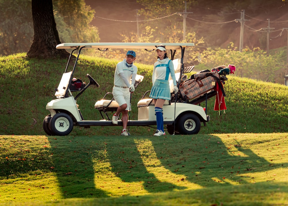 Two golfers standing next to a golf cart