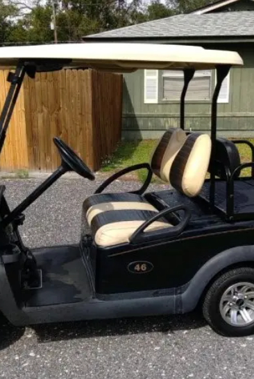 A black colored golf cart for sale standing outside.