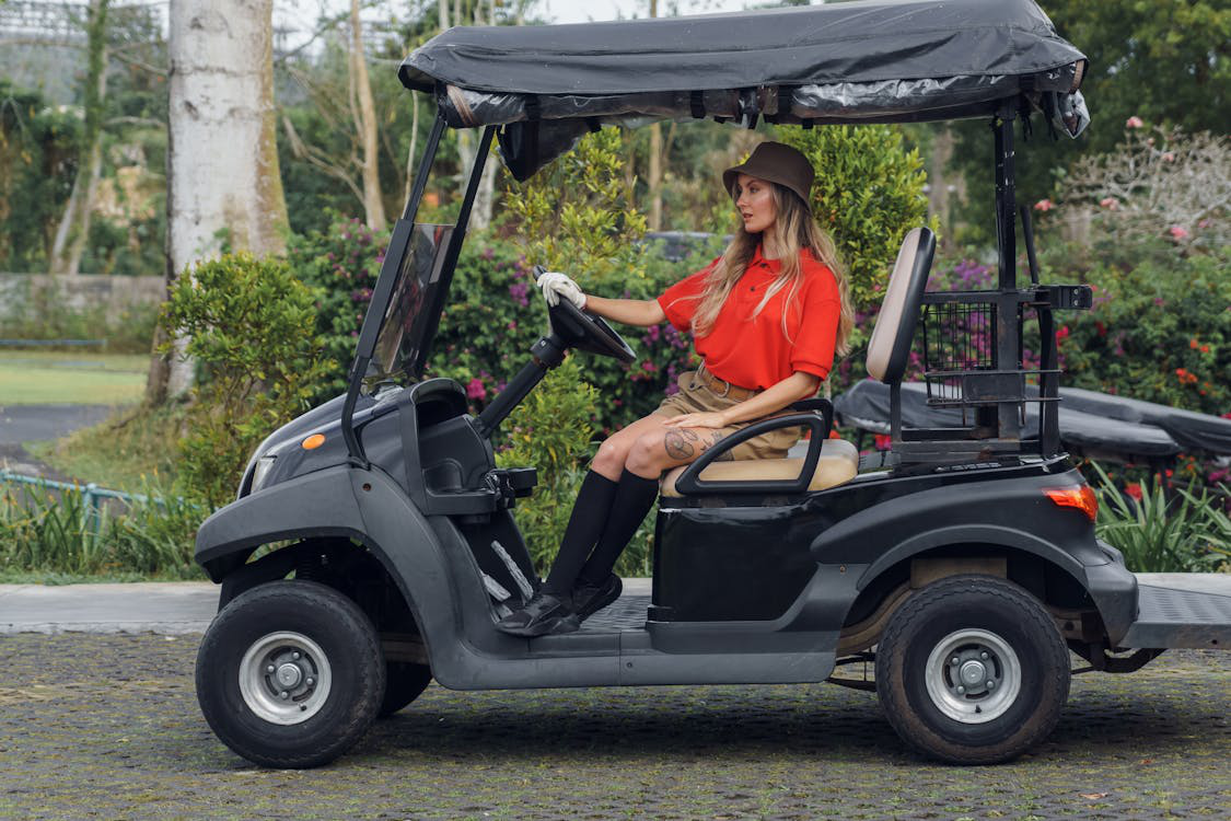 A person in a red polo shirt in a black golf cart