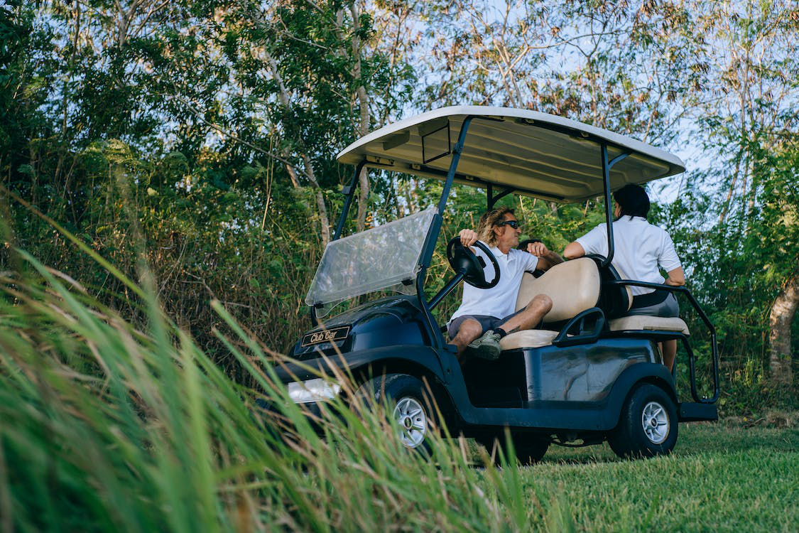 Two people in a golf cart with new golf cart tires
